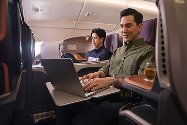 Mann arbeitet am Laptop in der Flugzeug-Businessclass.