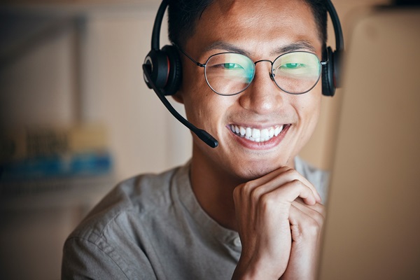 Lächelnde Person mit Headset bei der Arbeit am Computer