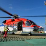 Helicóptero en primer plano sobre plataforma metálica. Al fondo, el mar, el cielo y el horizonte.