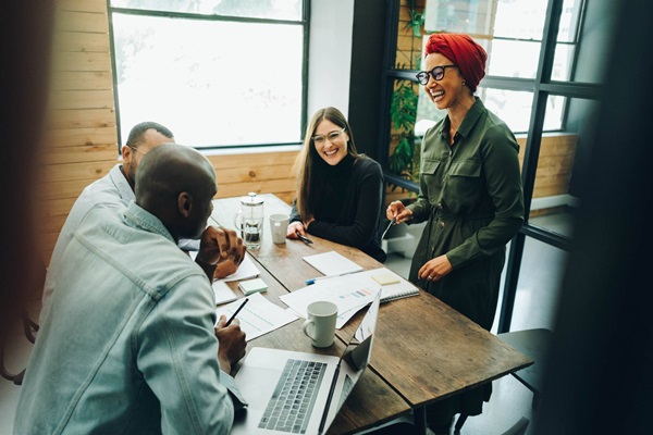 Cuatro empleados de diferentes razas y culturas se encuentran reunidos en una oficina.