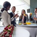 Dos mujeres y dos hombres de negocios brindan en un evento corporativo.