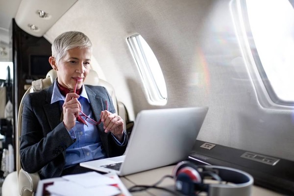 Mujer ejecutiva mira la pantalla de su ordenador portátil mientras viaja en cabina de primera clase.