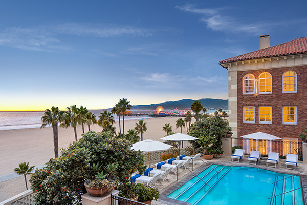 Beachfront hotel with pool and ocean view at sunset.