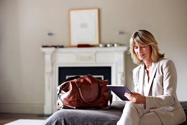 Woman in suit using tablet near leather bag.