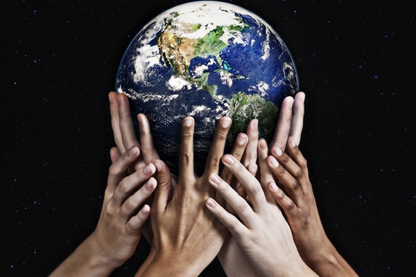 Diverse hands holding planet Earth together.